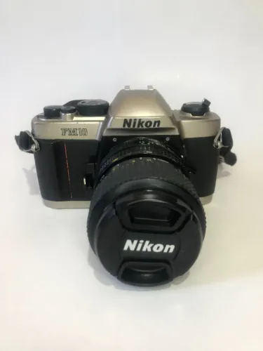 Câmera analógica Nikon FM10, com lente 35-70, possui alguns sinais de uso.
