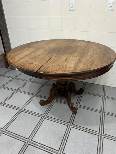 Mesa de jantar em madeira maciça, modelo clássico com pé central trabalhado.