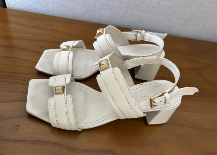Essa sandália de couro off-white com salto bloco e detalhes de tachas douradas