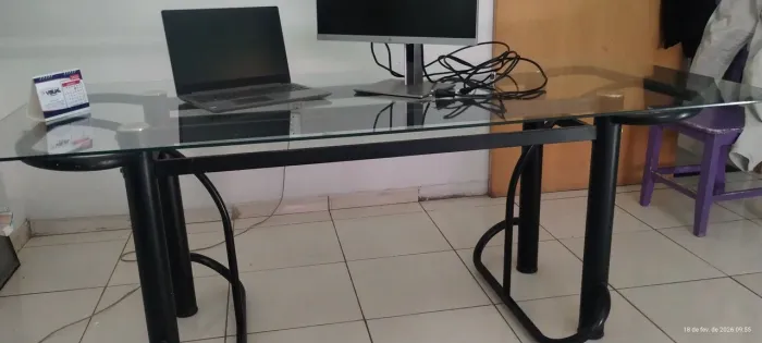 Mesa de vidro transparente, com suporte metálico.