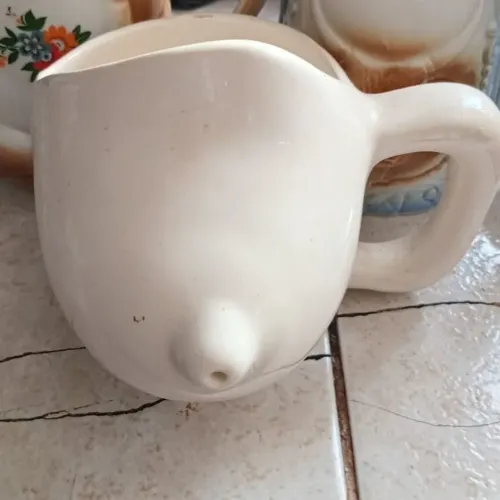 2 Canecas em cerâmica. Com design de um seio. E, Outra um caneca mais ousadas.