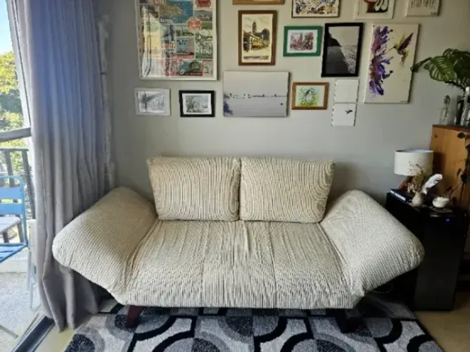Sofá-cama compacto com braços reclináveis e pés de madeira