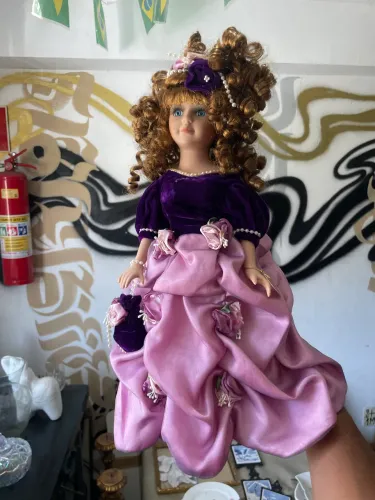 boneca de porcelana da marca Collector's Choice vestindo um vestido roxo e rosa