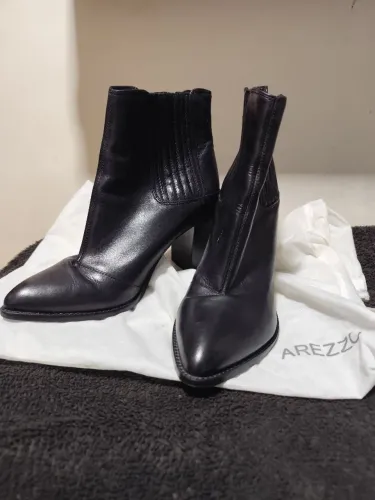 Bota preta de couro da marca Arezzo com bico fino e salto bloco.