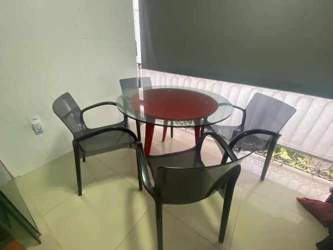 Mesa laqueada redonda com tampo de vidro e cadeiras de acrílico