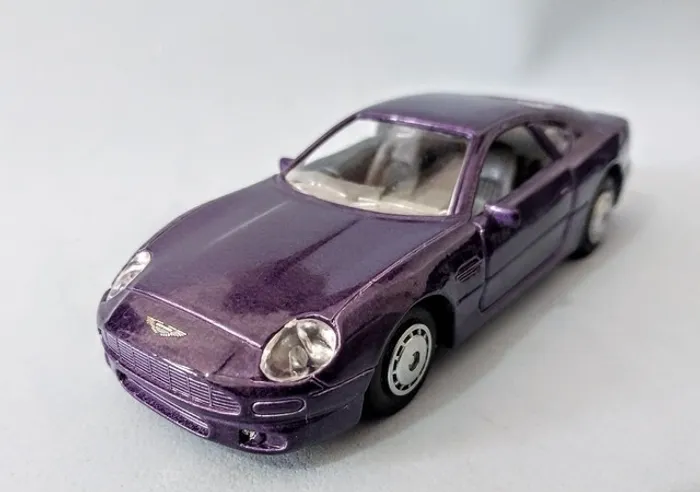 Miniatura Maisto<br>Escala 1:40 -Aston Martin DB7- Cor Roxo
