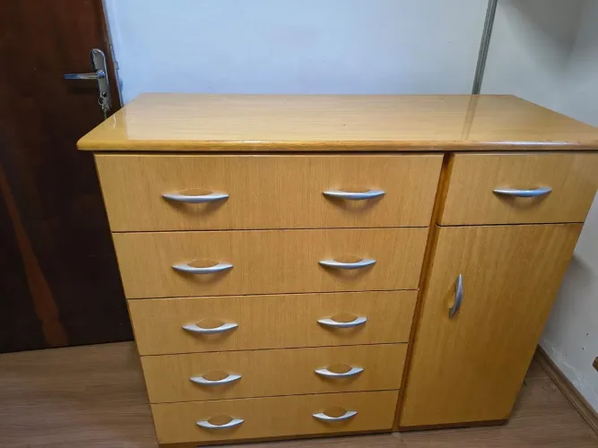 Cômoda de madeira com cinco gavetas e uma sapateira lateral com porta.