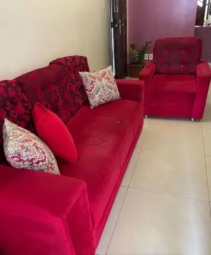 conjunto de sofá e poltrona de veludo vermelho, com leves marcas de uso