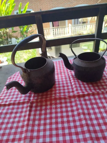 2 chaleiras de ferro antiga , sendo que uma tem um furo o que demonstra os anos de exixten