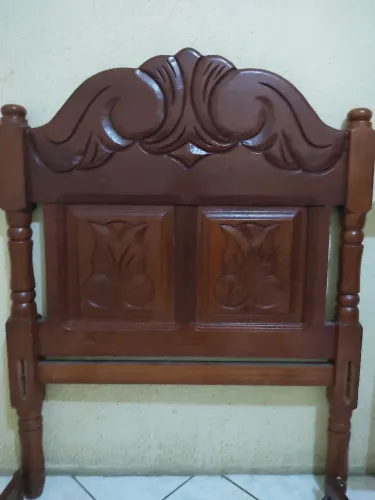 Cama de madeira maciça com cabeceira entalhada.