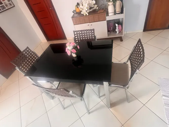 Mesa com 4 cadeiras, estrutura cromada, tampo de vidro preto.
