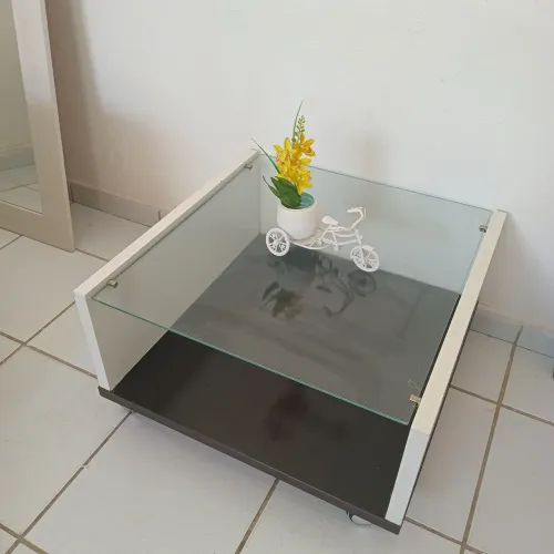 Mesinha de centro com tampo de vidro e rodinhas.