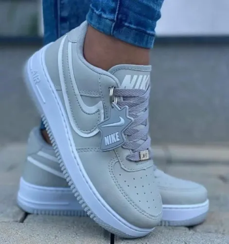 Nike Air Force 1 na cor cinza, acompanhado por um chaveiro decorativo 