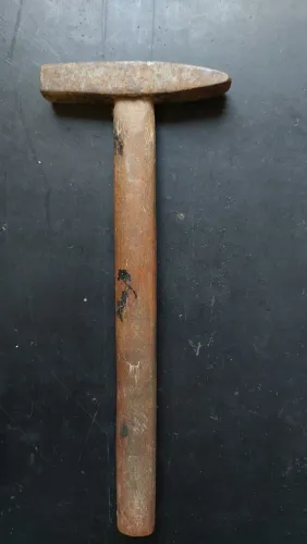 Martelo de pena antigo com cabeça de ferro forjado e cabo de madeira.