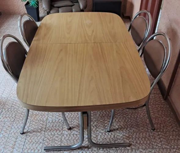 Mesa clássica e cadeiras com pés metálicos.