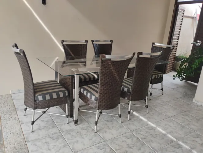 Mesa com tampo de vidro e seis cadeiras de alumínio e junco