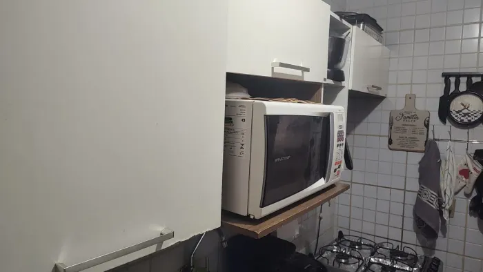 Armários de cozinha, acompanhado um microondas que ainda está em condições de uso.