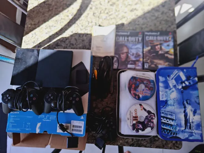 PS2 Slim Preto, na caixa com controles e jogos. Relíquia