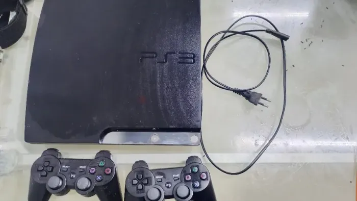 Playstation 3 com dois controles e uma fonte 