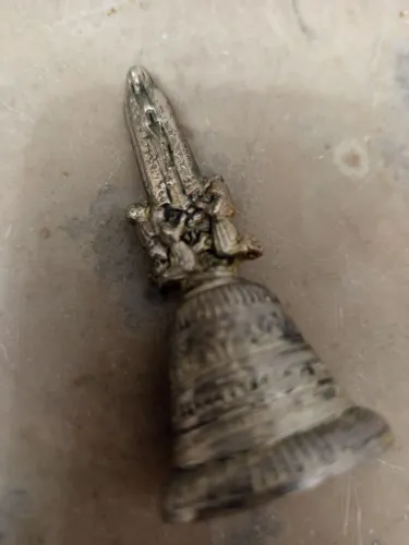 Sino Metal.Figuras que lembram Virgem Maria e outras ajoelhadas.