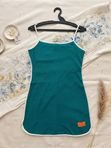 vestido curto verde-petróleo com alças finas e debrum contrastante em tom claro.