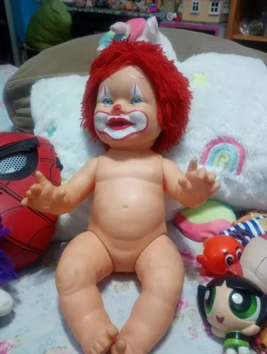 boneco bebê com cara pintada de palhaço,