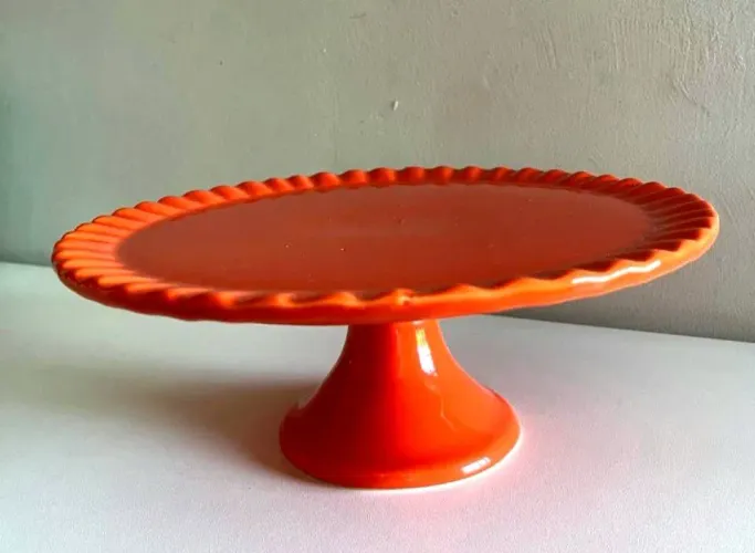 Boleira em cerâmica de cor laranja, ideal para servir bolos e decorar a mesa posta.