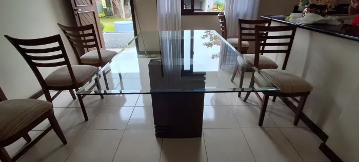 Mesa de jantar de vidro com base de madeira.