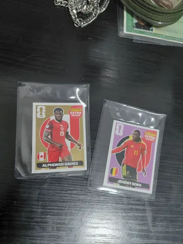 ALPHONSO DAVIES OURO/JEREMY DOKU REGULAR (ROXA) LEGENDS COPA 2026 PANINI
