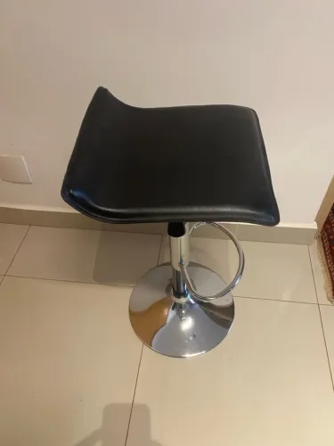 Banqueta em couro e aço, giratória e regulável.