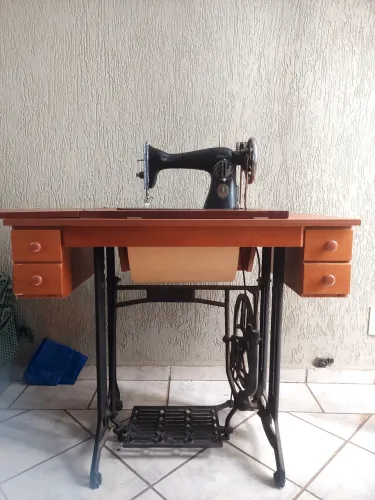 Máquina de costura antiga com gabinete e base de ferro fundido