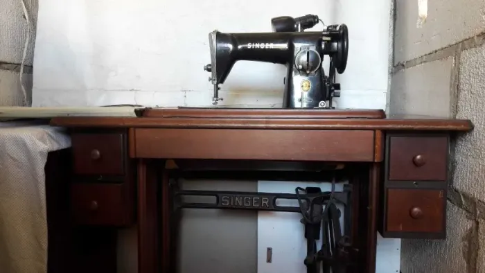 Máquina de costura Singer antiga com gabinete de madeira e pedal mecânico
