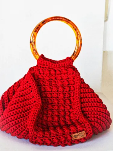 Bolsa de crochê com alça de acrílico e fechamento com zíper.