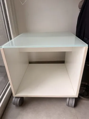 Mesa de cabeceira branca com tampo de vidro e rodízios