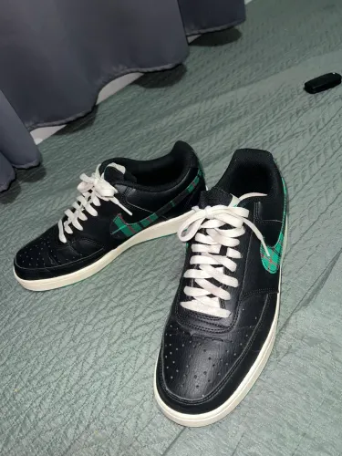 tênis Nike Court Vision Low em preto com detalhes do Swoosh em xadrez verde.