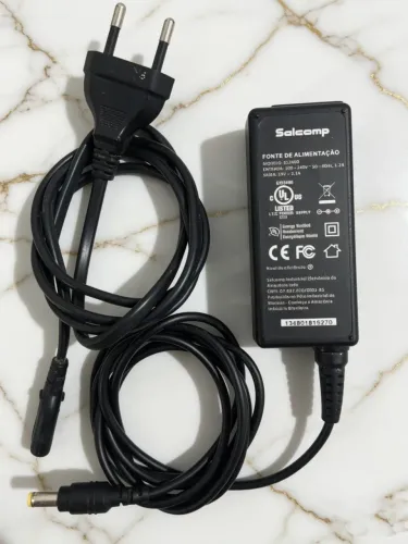 Fonte de alimentação original Salcomp, entrada 100-240V e saída 19V 2.1A.
