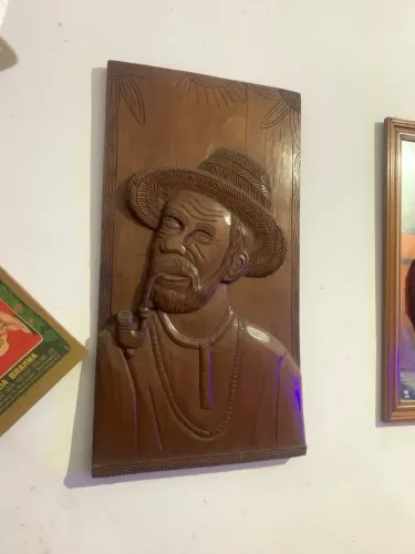 Escultura em madeira entalhada de homem com cachimbo