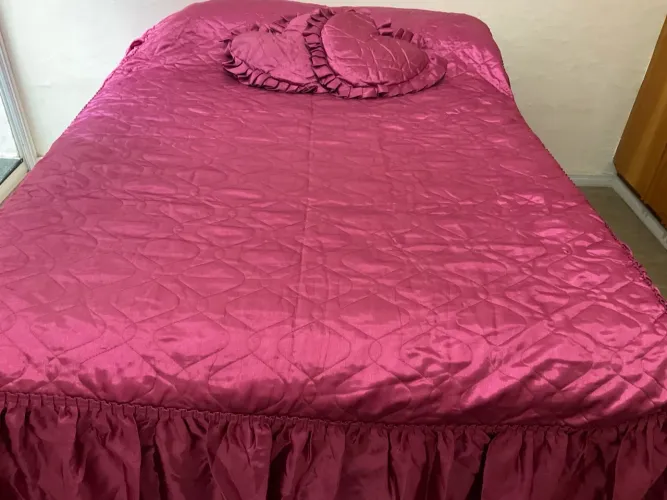 Cobre-leito rosa com almofadas de coração