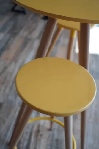 Mesa bistrô com 2 banquetas, tampo na cor amarela e pés madeira clara