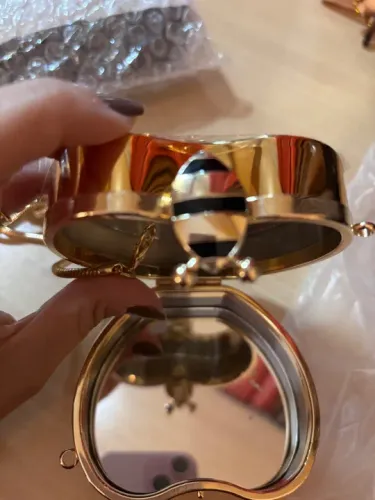 Bolsa de mão dourada em formato de coração com espelho