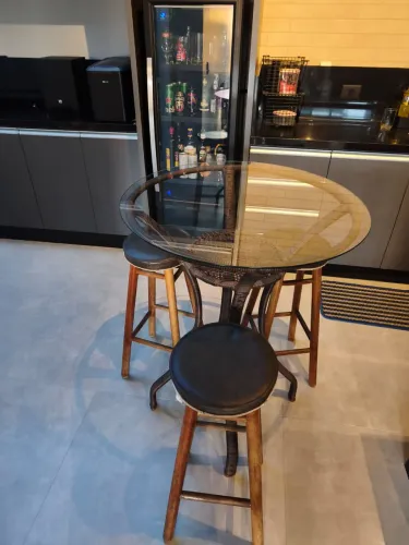 Mesa bistrô com banquetas e tampo de vidro.