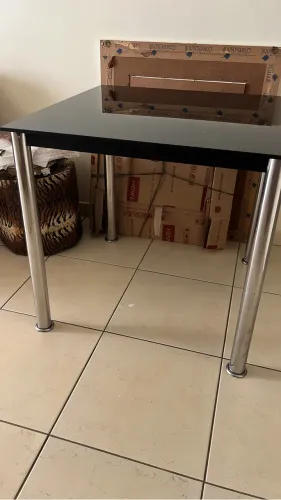 Mesa com tampo de vidro fumê e pés de inox.