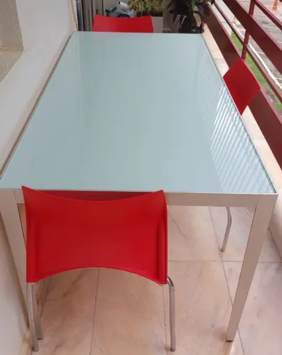 Mesa de jantar com vidro temperado e alumínio com quatro cadeiras de plástico e metal 