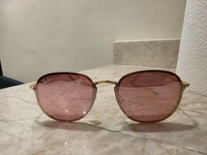 óculos de sol redondo com lentes cor rosa e armação hastes douradas