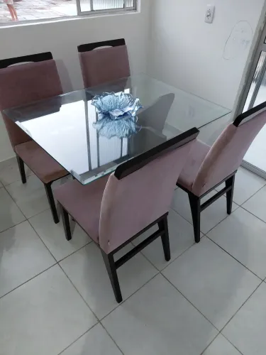 Mesa de jantar com tampo de vidro, cadeiras e base em madeira.