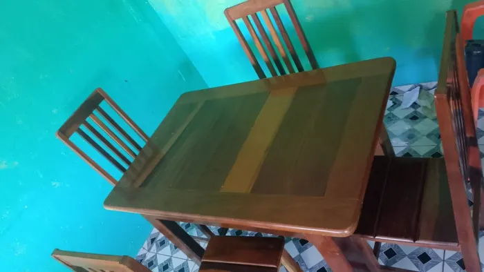 Uma mesa d madeira rústica com 4 cadeiras e acompanha um jogo de mesa
