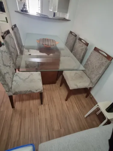 Mesa de jantar com tampo de vidro e seis cadeiras.