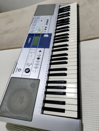 Teclado Yamaha PSR-E323 na cor prata.