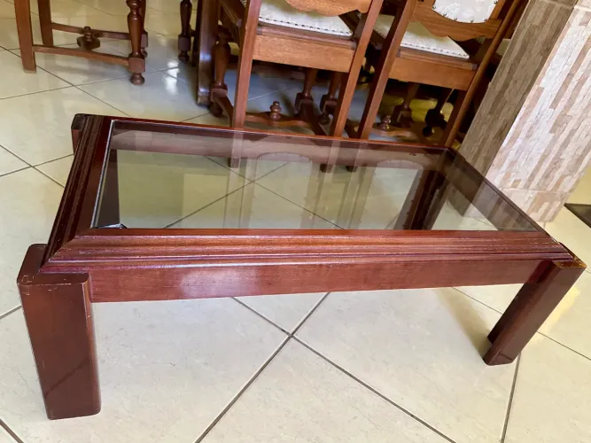 Mesa de centro elegante e resistente, com estrutura em madeira e tampo de vidro fumê.