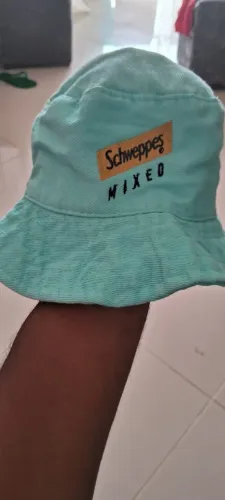 chapéu estilo bucket hat de cor verde-água com um bordado da marca de bebidas Schweppes